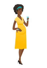 Pregnant woman holding a glass of water and pills.