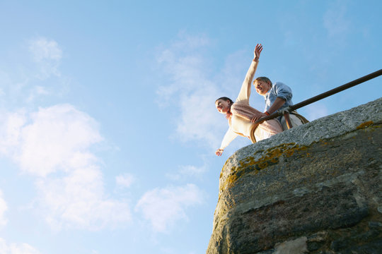 Couple playing on edge of stone wall