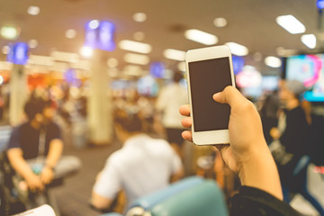 Close Up on smart phone in woman hand and blurred image of a people in the airport background.
