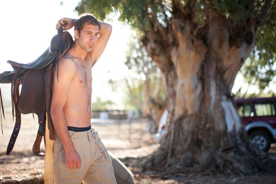 Young man carrying saddle