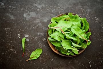 Fresh swiss chard leaves (or mangold) in bowl on brown background
