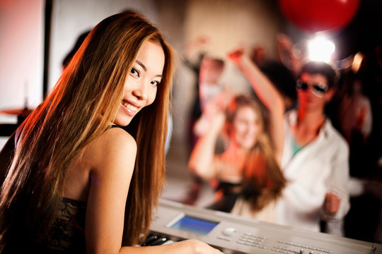Young woman playing keyboard with people dancing