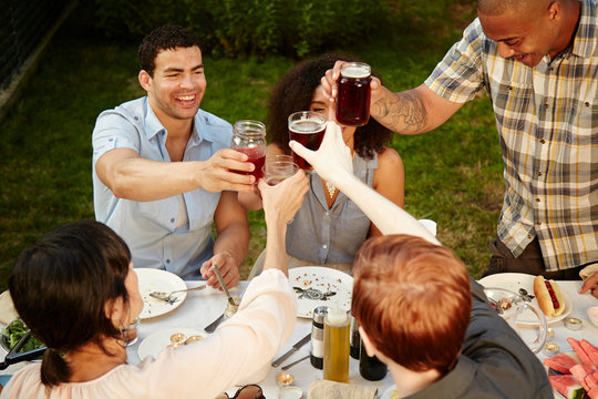 Group of friends toasting with drinks at garden party