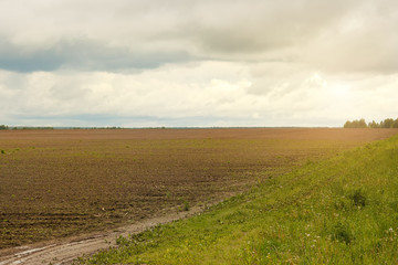 Fototapeta na wymiar village plowed field on a cloudy day