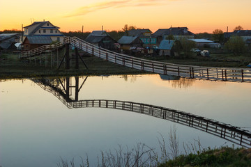 hanging wooden bridge over the river at sunset