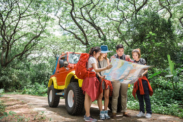 Young hipster friends With Backpacks in forest look at map