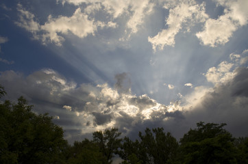 cloudy blue sky with rays of light coming out of the clouds