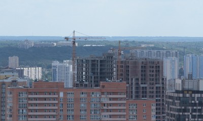 Fototapeta premium Building crane and building under construction against blue sky