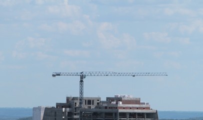 Building crane and building under construction against blue sky