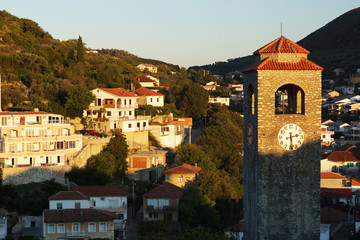 Obraz premium Dawn in a small town, the sun illuminates a stone chapel with a red tiled roof