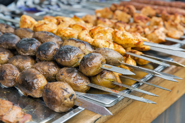 Potatoes and shish kebab on skewers fried on grill outdoors