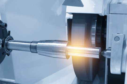The cylindrical grinding machine with the steel shaft.Hi precision manufacturing concept.