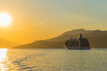 Obraz premium A large liner sails in the rays of the sunset along the Boka-Kotorska Bay. Montenegro.