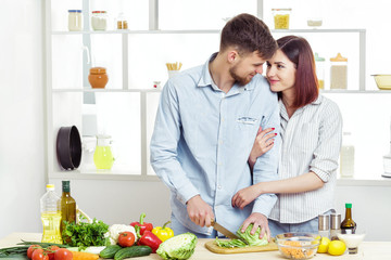 Loving happy couple preparing healthy salad of fresh vegetables in  kitchen