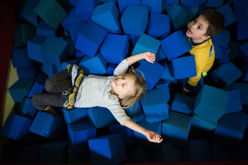 Young boy and girl playing in foam cube pit, overhead view