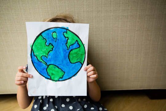 Young girl holding planet earth art in front of face