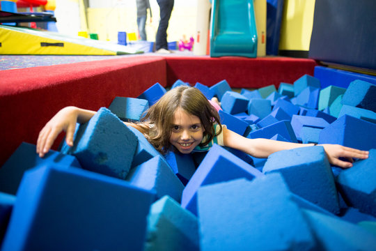 Young girl playing in foam cube pit
