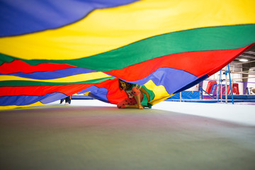 Children playing underneath colourful parachute
