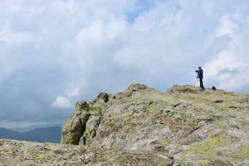 Elderly man takes photos with his camera on tripod high on the rocks of Belintash - an ancient Thracian sanctuary with stellar map dedicated to god Sabazios - Dionysus, Rhodope Mountain, Bulgaria