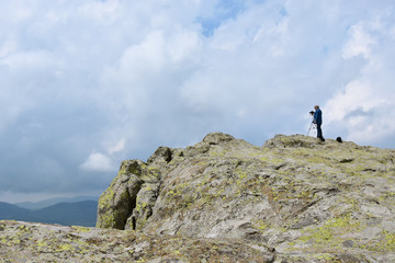 Elderly man takes photos with his camera on tripod high on the rocks of Belintash - an ancient...