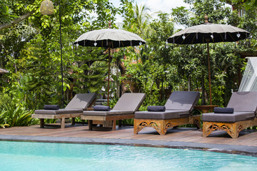 Swimming pool and deck chairs in tropical garden. Island Bali, Ubud, Indonesia