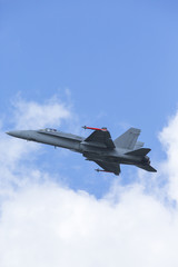 Modern jet fighter flying close by. Closeup shot of a tactical fighter against cloudy and blue sky.