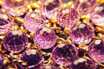 Fototapeta na wymiar Purple plastic jewelry texture with golden chains