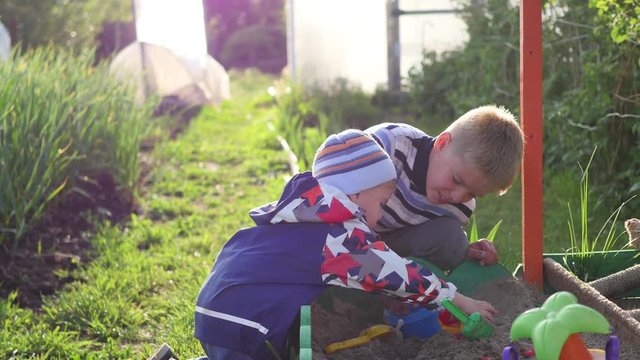 Children play with toys in the sandbox. Entertainment and outdoor games. Summer sunny day