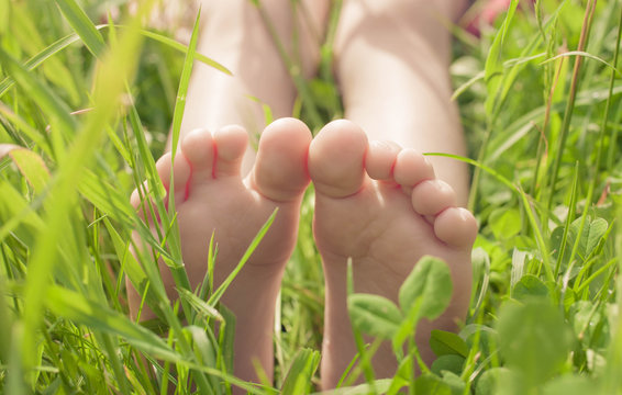 Kid bare feet in green grass. Lifestyle concept