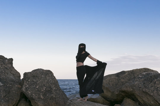 Oriental beauty in a veil on the background of the sea and the moon,symbols of the east