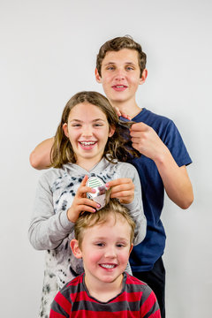 Family louse treatment. Three children comb each others hair to look for head ice, loughing.