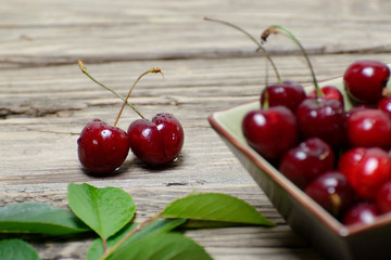 Fresh cherries in a square ceramic dish on wooden background 