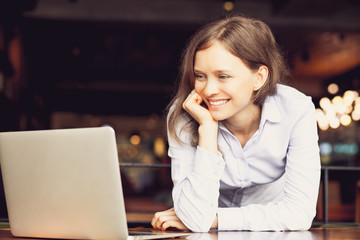 Positive young woman using laptop at table