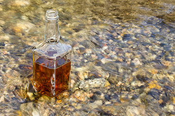 Bottle of the whiskey is cooled in the mountain river