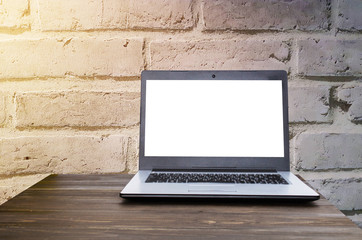 Fototapeta premium Laptop computer with white blank screen on wooden table with brick wall background, selective focus, copy space, sunlight effect, business working, online social media and searching data concept