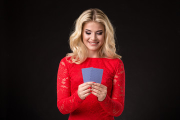 Young beautiful emotional woman with cards in hands on a black background in the studio. Poker