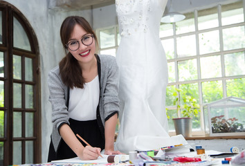 Young female fashion designer are working on drafting a new  clothes in studio.