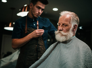 Senior man visiting hairstylist in barber shop.