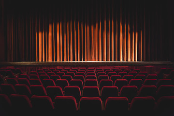 Red armchairs and stage with closed curtain illuminated by projectors - 161280427