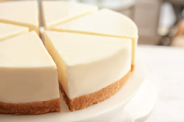 Dessert stand with delicious sliced cheesecake on table