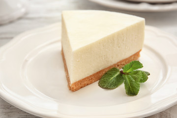 Plate with piece of delicious cheesecake on table