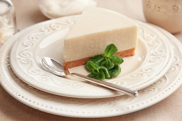 Plate with piece of delicious cheesecake on table