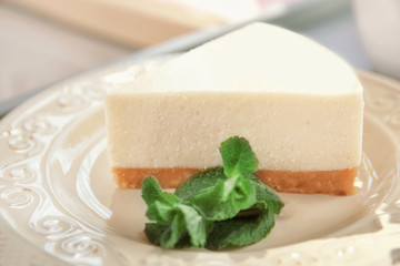 Plate with piece of delicious cheesecake on table