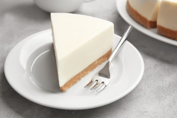 Plate with piece of delicious cheesecake on table