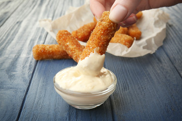 Woman eating cheese sticks with sauce on table