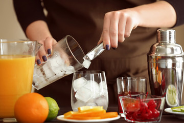 Woman preparing Tequila Sunrise cocktail on kitchen table