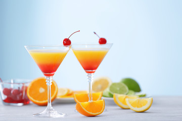 Glasses of Tequila Sunrise cocktail with citrus slices on wooden table
