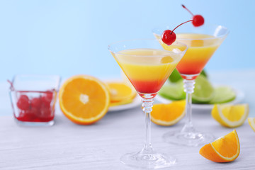 Glasses of Tequila Sunrise cocktail with citrus slices on wooden table