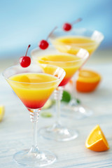 Glasses of Tequila Sunrise cocktail with citrus slices on wooden table