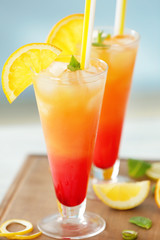 Glasses of Tequila Sunrise cocktail with citrus slices on wooden table